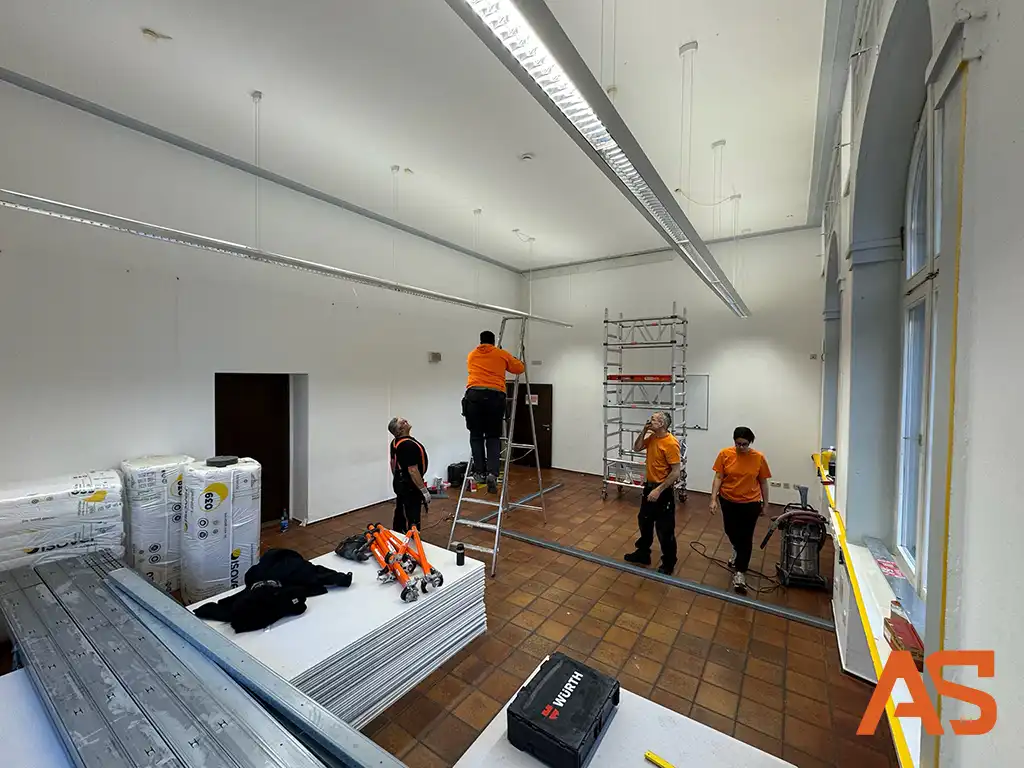 Montagebeginn des Metallständerwerks: Einmessung und Aufbau der Unterkonstruktion in hohen Räumen.