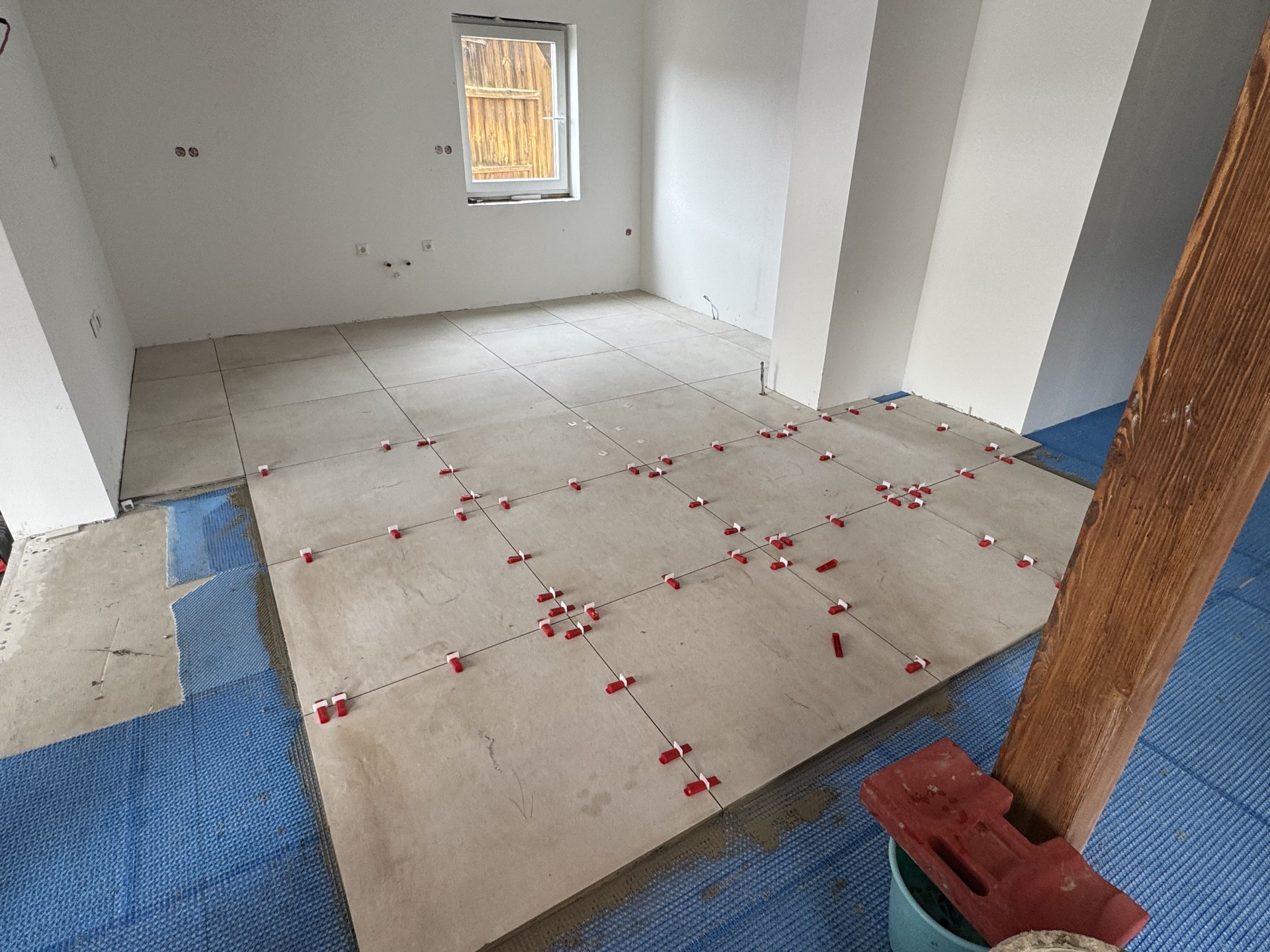 Bodenfliesen 80 × 80 im Nivelliersystem, im Hintergrund die noch offene Entkopplungsmatte